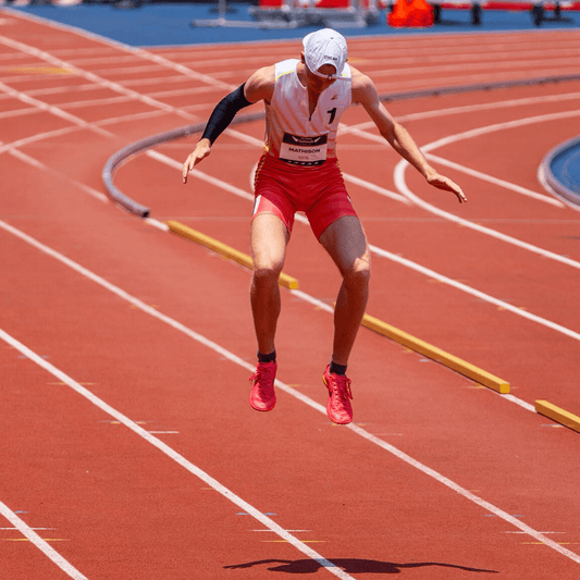 Male runner jumping on track wearing Male runner wearing SockMoose SpeedyMoose Ankle Tab 2.0 gray